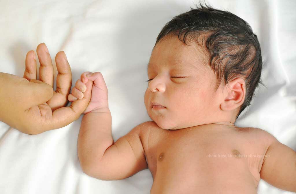 the two-week baby sleeps on holding his moms finger
